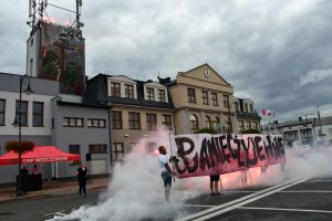 Zdjęcie: Mężczyźni trzymający baner z napisem Pamięć żyje w nas w koło dym biało czerwony